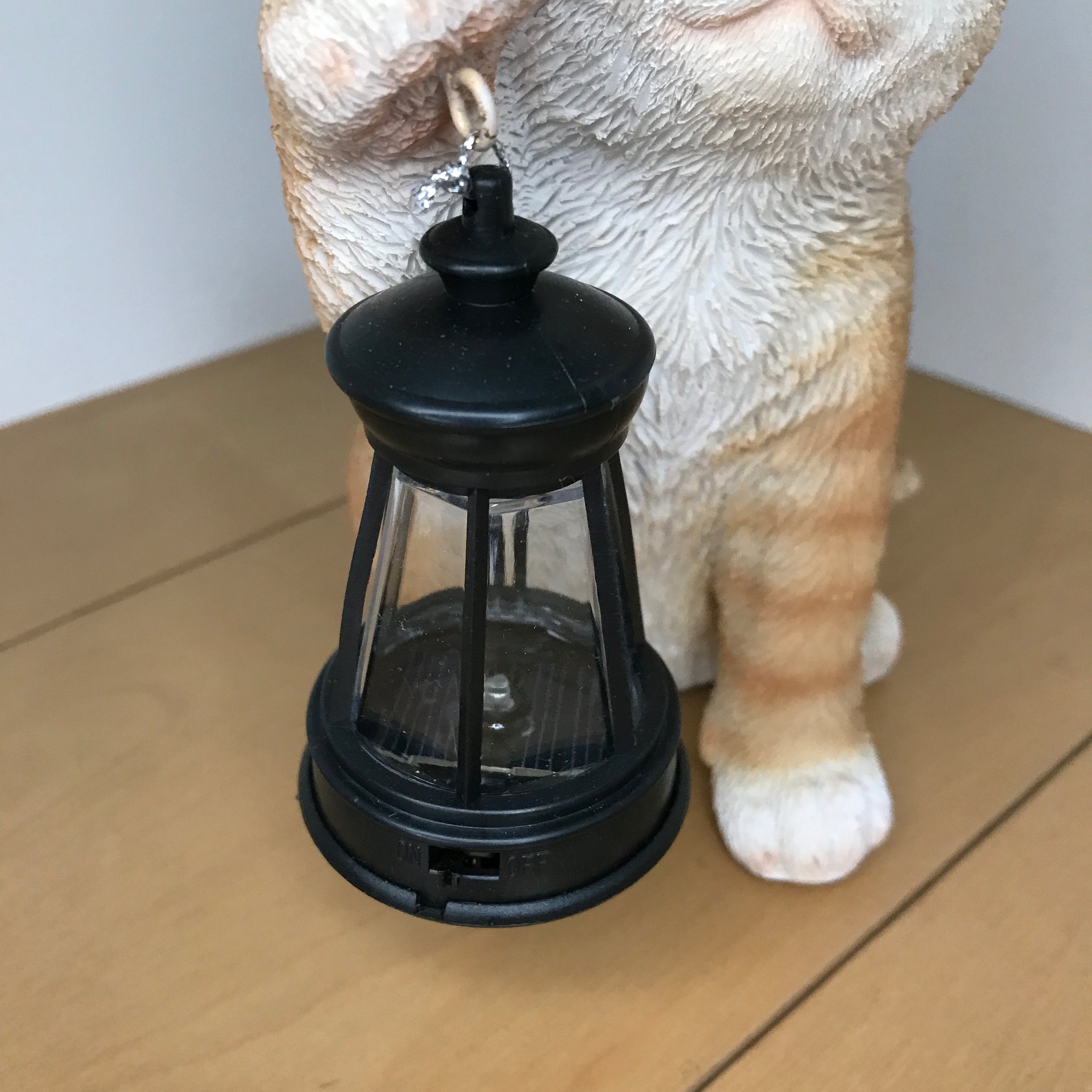 ソーラーランプを右手で持ち上げる茶トラ猫｜WooBia（ウービア